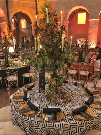 Montaje nocturno con iluminación cálida y arreglos florales altos en interior