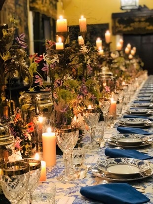 Mesa larga iluminada con velas y centros de mesa florales en tonos tierra